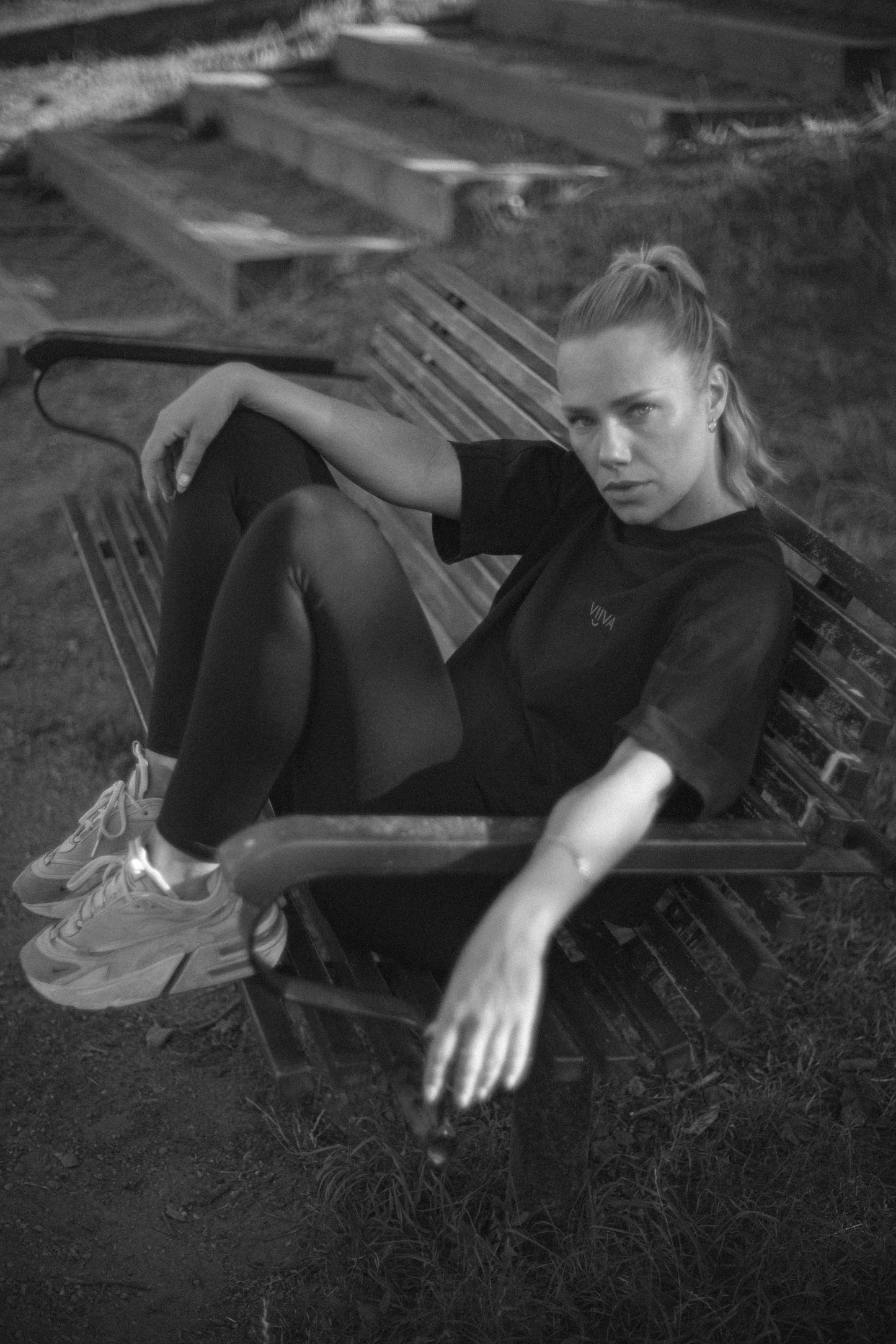 Woman sitting on a chair outdoors with a black and white color scheme, wearing VIIVA black cotton t-shirt
