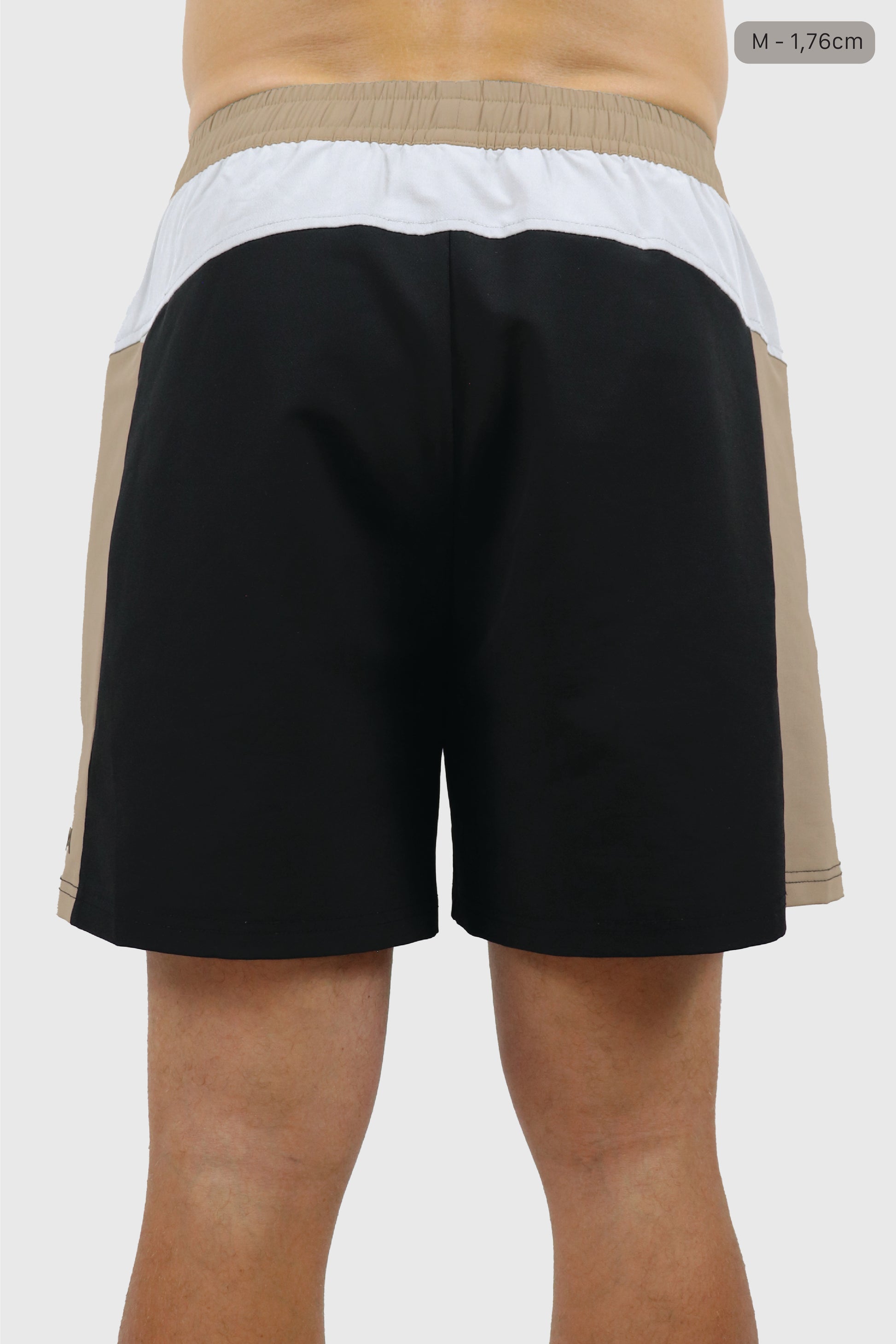 Color-blocked men's shorts with black, beige, and white sections, on a white background