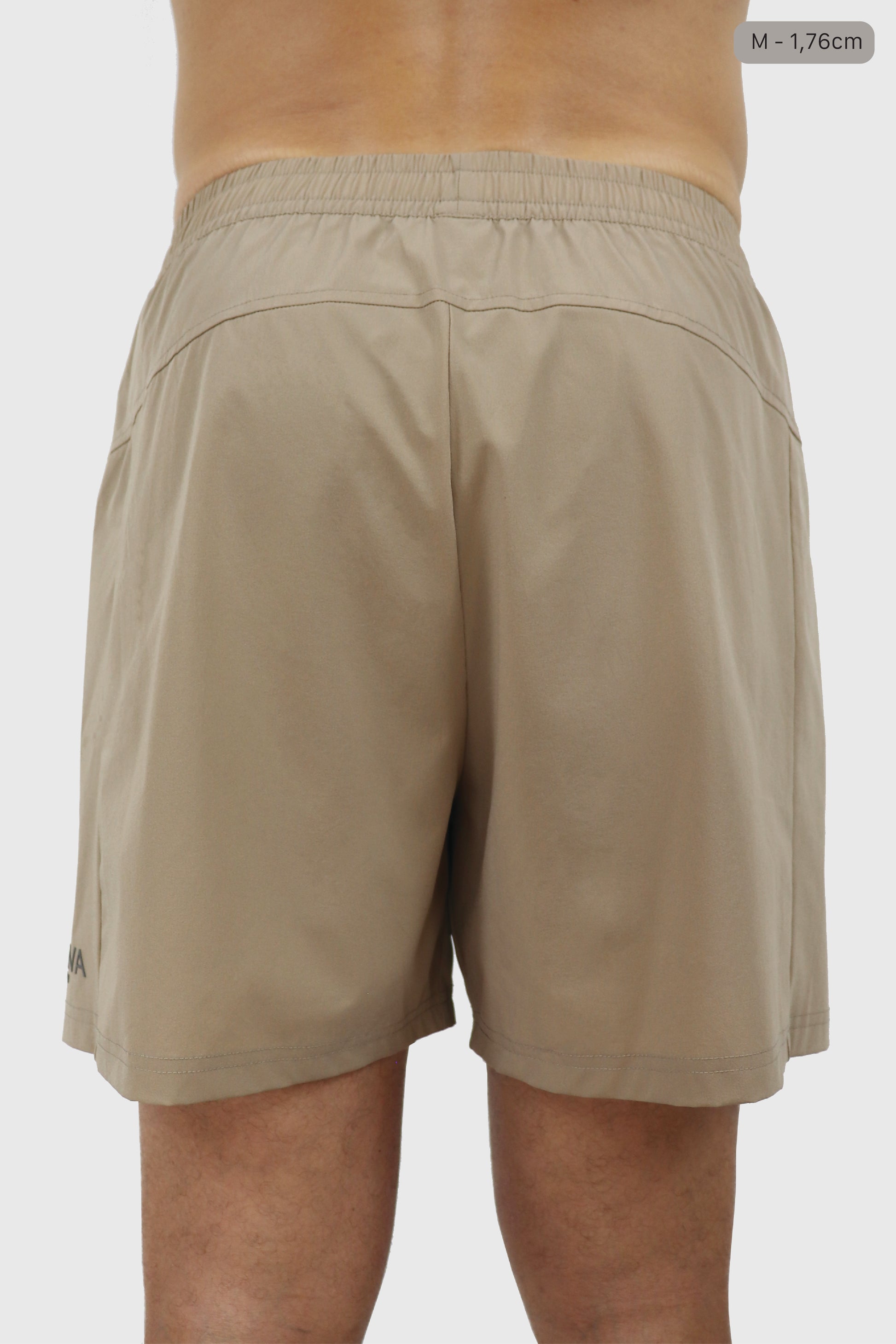 Person wearing beige men's shorts on a plain background