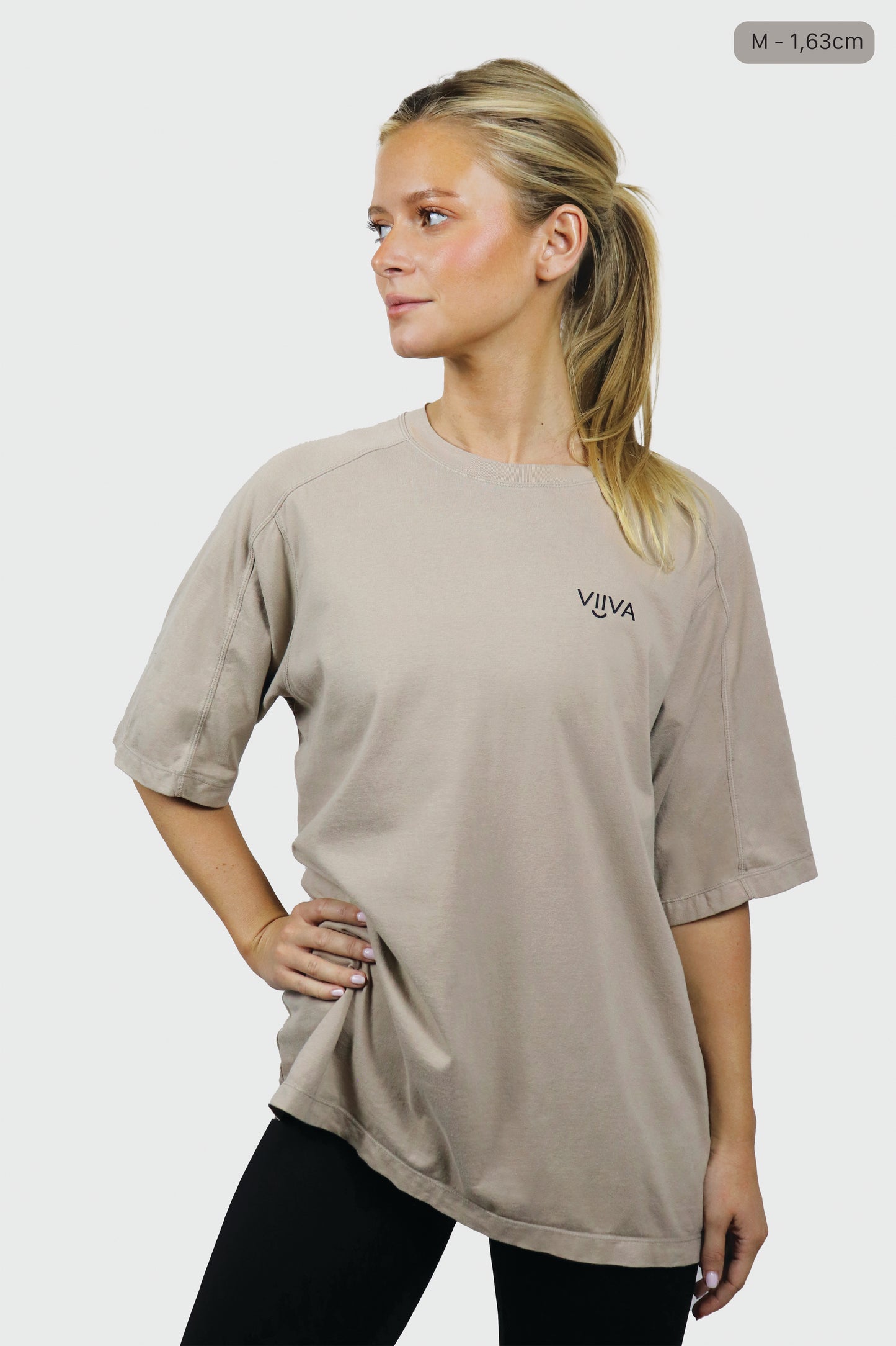 Woman wearing a beige cotton t-shirt with 'VIIVA' logo on a white background