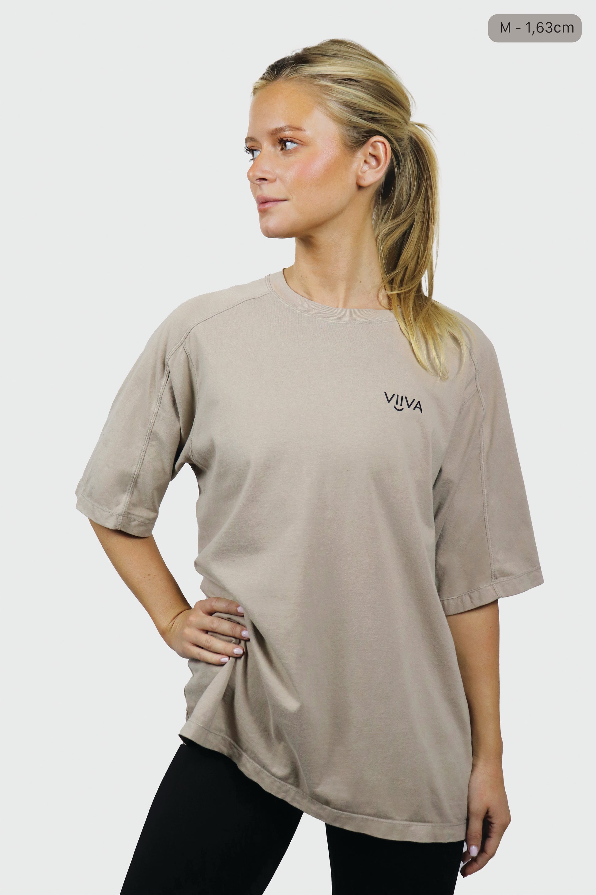 Woman wearing a beige cotton t-shirt with 'VIIVA' logo on a white background