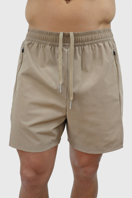 Beige men's shorts with elastic waistband, drawstrings and zipper pockets worn by a person on a white background