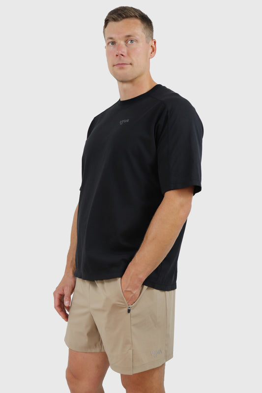 Man wearing a black cotton t-shirt and beige shorts on a white background