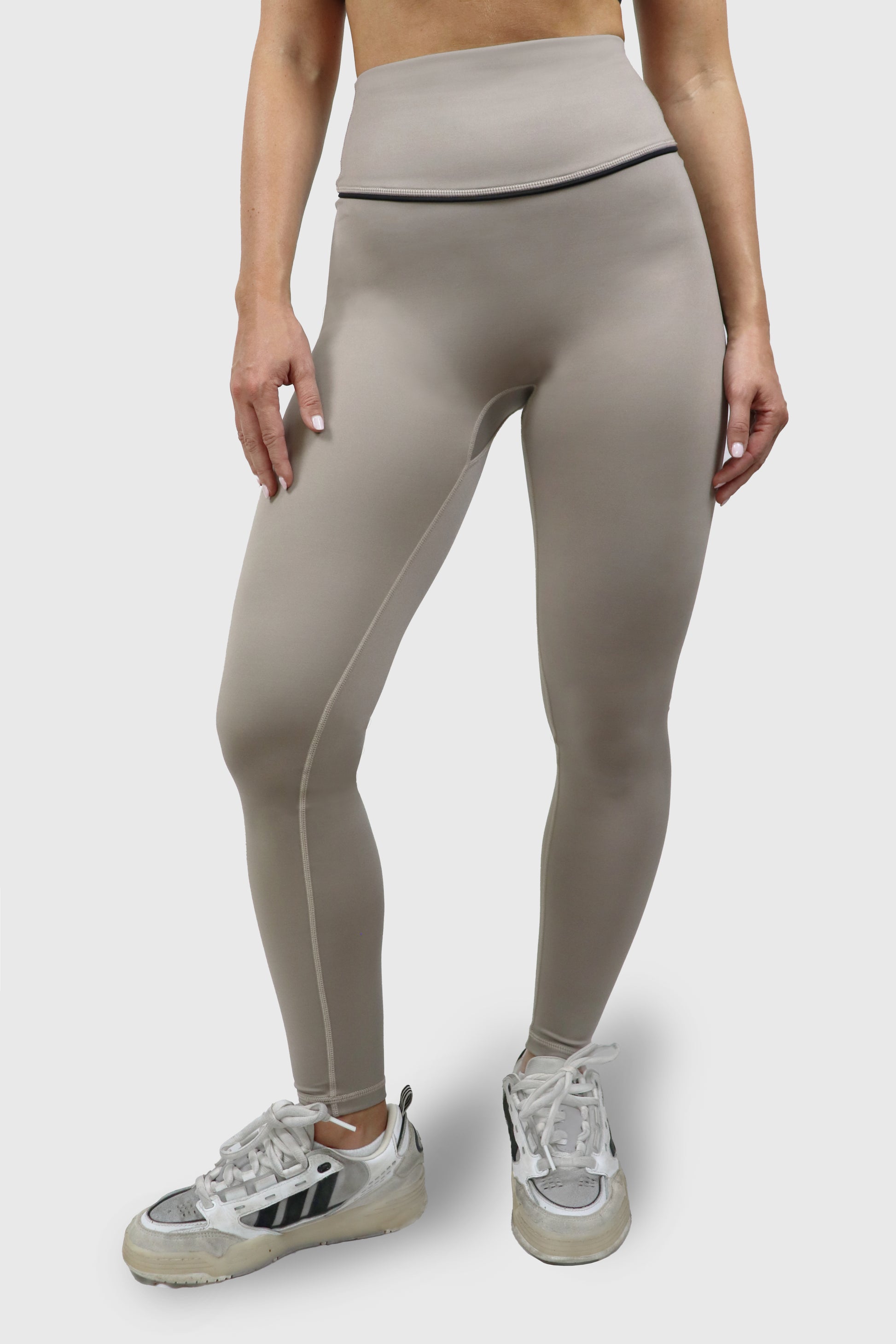 Woman wearing a beige taupe legging with black accents and details on a white background