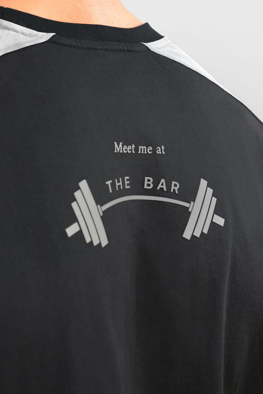 Man wearing cotton black and white t-shirt with grey 'meet me at the BAR' barbell graphic print at the back.