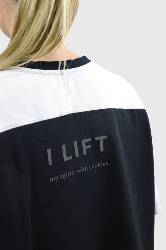 Woman wearing a black and white cotton t-shirt with the phrase 'I LIFT my spirits with cookies' printed in grey at the back