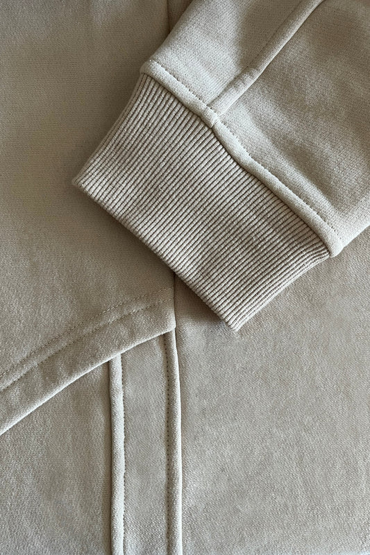 Close-up of beige cotton jersey fabric with a focus on texture and stitching.