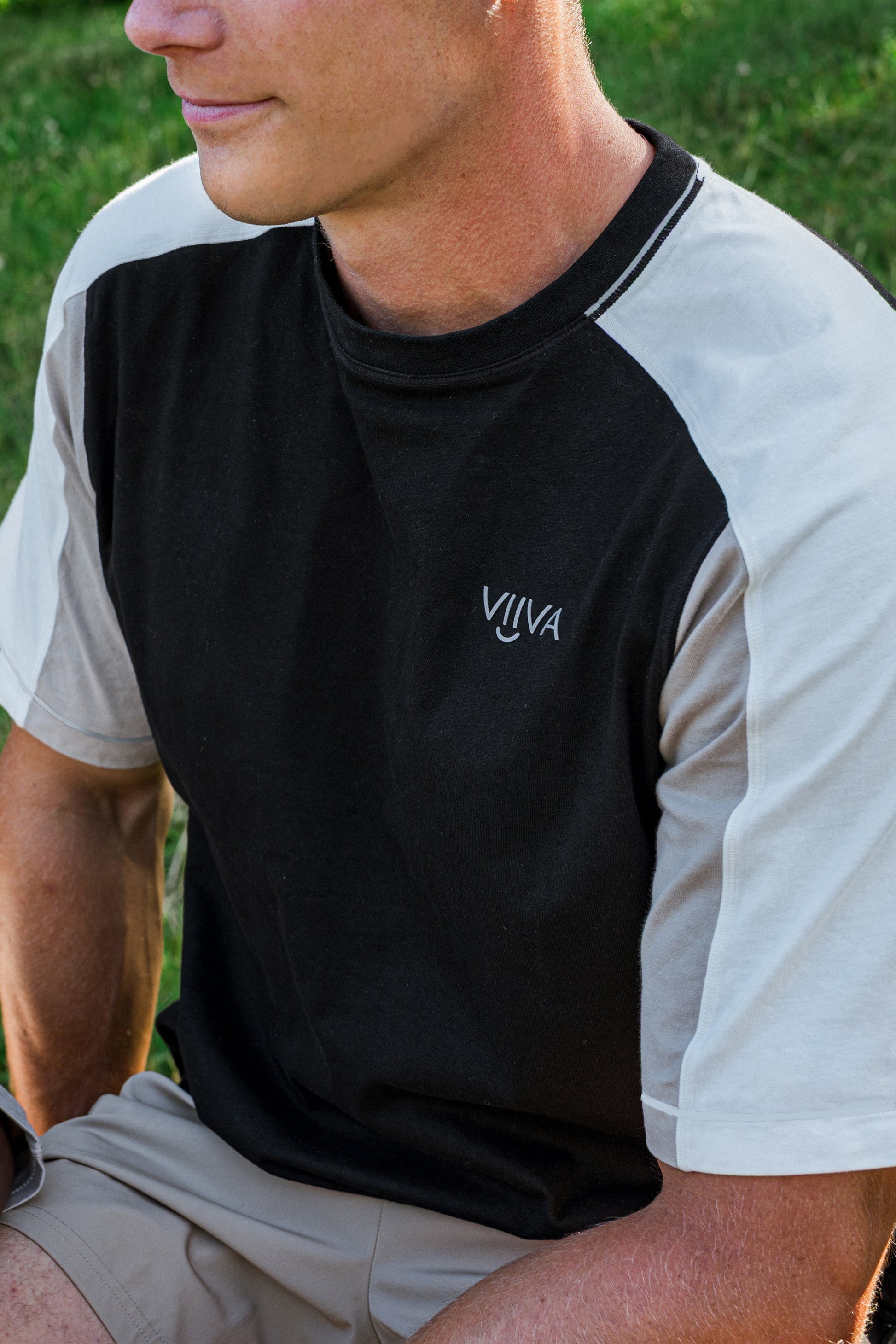 Man wearing cotton black, white and beige t-shirt, with raglan sleeves, and small logo print at front
