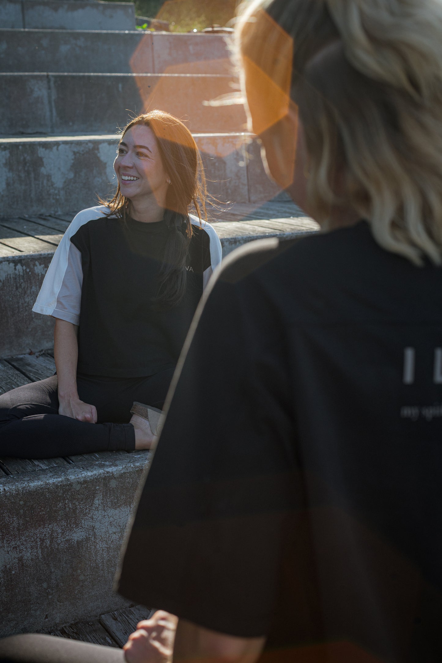 Woman wearing cotton t-shirt in black, white and beige with raglan sleeves sitting outside